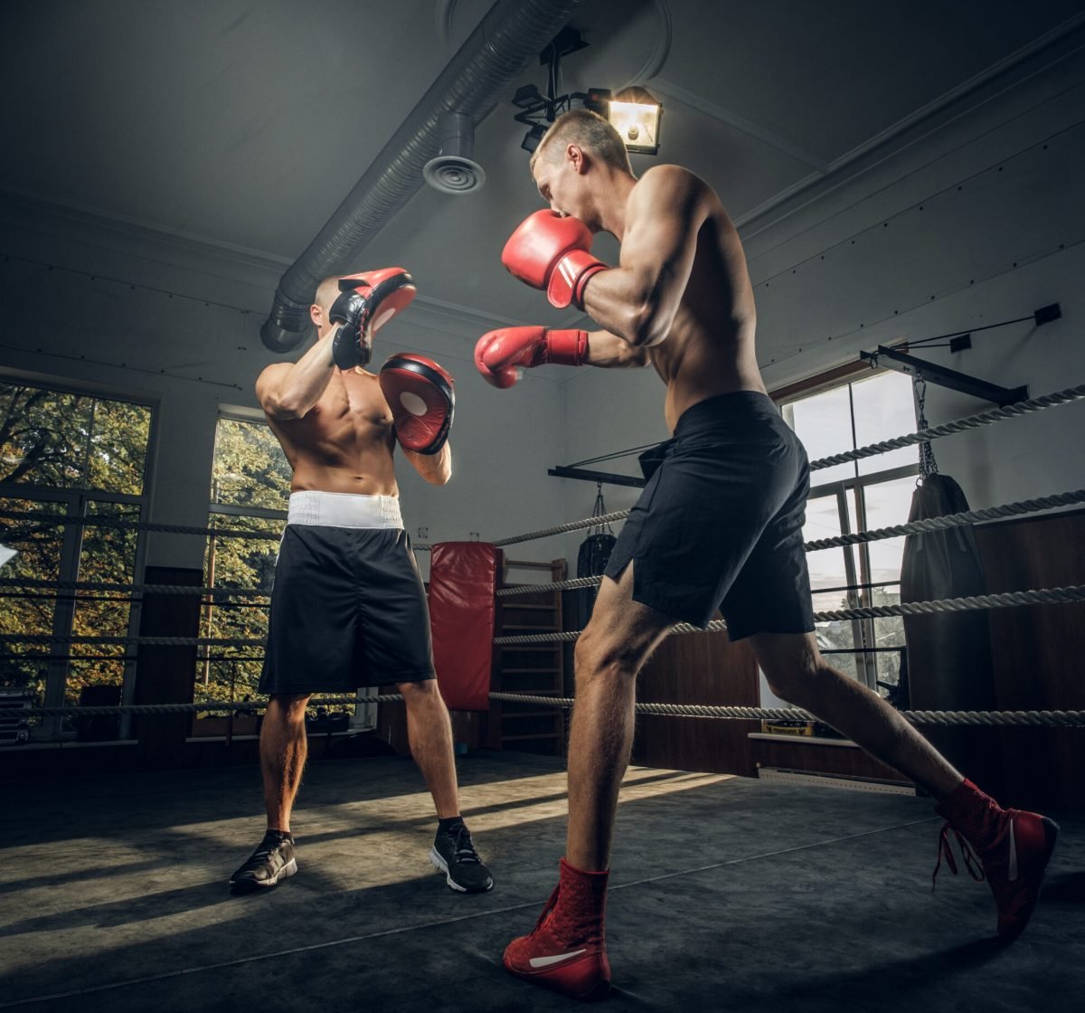 Young boxing trainer and his new student have a training on boxing ring.
